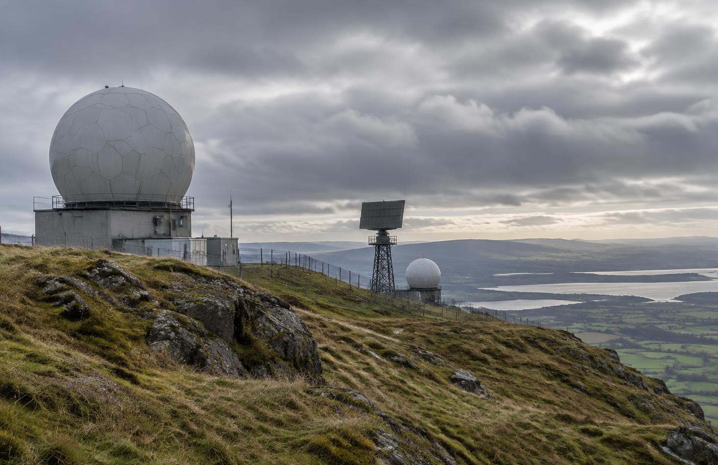 Generic radar and sensor arrays on a British hillside beneath grey clouds